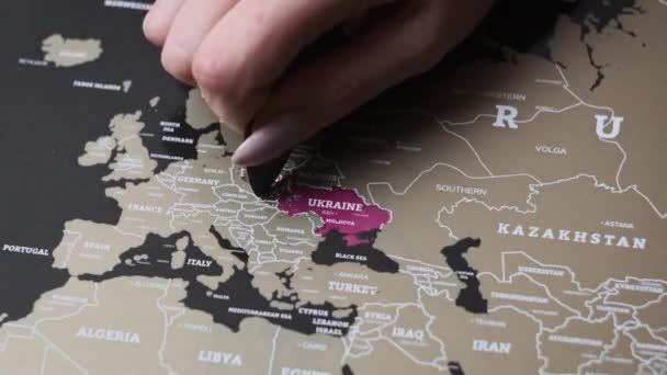 女性の手はポーランドの国とのスクラッチマップの表面を引っかきます ヨーロッパ諸国とのスクラッチ世界地図 クローズアップ スクラッチは旅行地図上の国を訪問しました スクラッチマップ上の国を消去する — ストック動画
