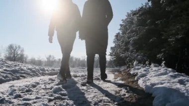 İki kız kış ormanında el ele yürüyorlar. Yavaş çekimde, dikiz aynasıyla. Parlak güneşe karşı kar yolunda yürüyen kadın kız arkadaşlar. Sevgi dolu bir çift adımın arka görüntüsü. LGBT, lezbiyen