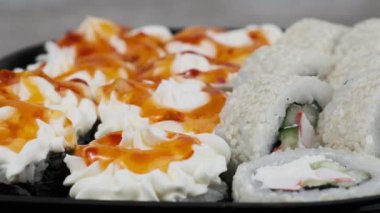 Suşi plastik kutuda döner, yakın plan. Philadelphia peynirli taze Japon suşisi, nori, susam, somon filetosu pilav, avokado ve salatalık. Plastik konteynıra konmuş suşi, paket yemek..