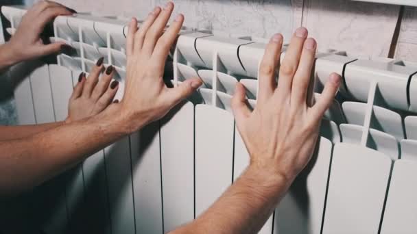 冷凍男性と女性の手は ホームラジエーターに触れ 暖かくしようとします 家庭用暖房問題 寒い季節の概念の間の家の温度 手はバッテリーを加熱して暖められます アパートの寒さ — ストック動画