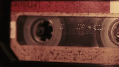 The cassette is played in a tape recorder in soft flickering candlelight, close-up. Yellow audio cassette in the deck rotates. Vintage sound recording in an old retro recorder. Audio Cassette playback