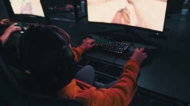 Bilgisayar kulübündeki bir çocuk oyun sandalyesinde oturup atış oyunu oynuyor. Esport Siber Kulübü 'nde kulaklık takan ve neon ışıkları video oyununa odaklanan bir genç. E-spor, hobi, sanal turnuva