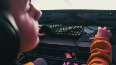 Bilgisayar kulübündeki bir çocuk oyun sandalyesinde oturup atış oyunu oynuyor. Esport Siber Kulübü 'nde kulaklık takan ve neon ışıkları video oyununa odaklanan bir genç. E-spor, hobi, sanal turnuva