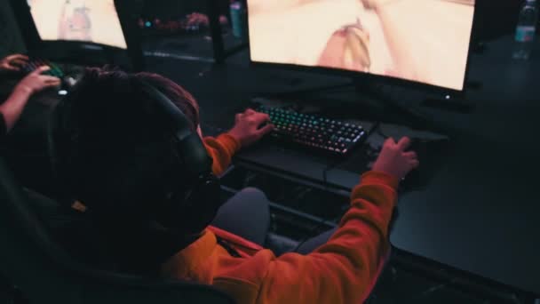 计算机俱乐部的男孩坐在游戏椅子上监视射击游戏 青少年们在一家配备霓虹灯的Esports网络俱乐部的耳机里 专注于电子游戏 电子体育 业余爱好 虚拟比赛 — 图库视频影像