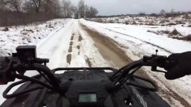 First-person view of a man riding a quad bike on snowy terrain, steering wheel view. POV control ATV on a snow-covered path in winter. Riding a four-wheeled in a snowy area. Vocation, off-road racing