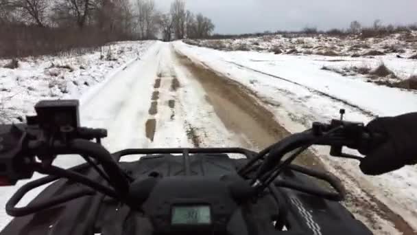 第一眼看到的是一个男人骑着一辆四轮驱动的自行车在雪地上 方向盘看到 越野车控制着冬季白雪覆盖的路上的越野车 在雪地里骑四轮车 越野赛 — 图库视频影像