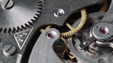 Clock mechanism rotates close-up. The working mechanism of round stopwatch spinning in macro. Detailed view of old retro clockwork gears, cogwheels and pendulum movement inside the ancient metal watch