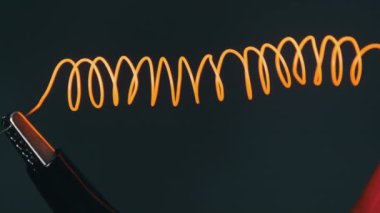 Nichrome filament connected to power wires is heated to red under the influence of a large current. Electric spiral wire heater heating the air and glowing. High metal resistance. Electric strength.