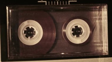 Klasik kayıt cihazında ses kasedi oynatıcısı. Eski şeffaf ses kasedini çalan bir pikap, yakın plan. Retro bantlar güvertede dönüyor. Konuşmalar kaydediliyor, 80 'ler, arşiv kaydı, çağrı