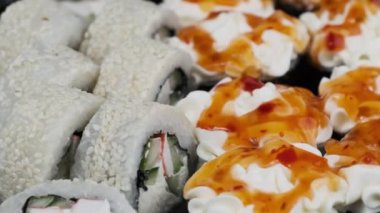 Suşi plastik kutuda döner, yakın plan. Philadelphia peynirli taze Japon suşisi, nori, susam, somon filetosu pilav, avokado ve salatalık. Plastik konteynıra konmuş suşi, paket yemek..