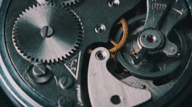 Clock mechanism rotates close-up. Vintage round stopwatch mechanism working in a macro. Old retro clockwork gears, cogwheels, and pendulum movement inside the ancient metal watch.