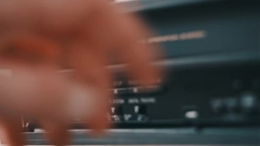 Male hand pulls out VHS from a vintage videotape recorder. Eject VHS tape cassette from a VCR player on a desk with many archived video cassettes. VHS retro player. Concept home video, old technology