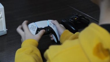 Oyun konsolunda oyun. Genç bir masada otururken elinde bir joystick 'i kontrol ediyor, yakın plan. Çocuk, eğlence merkezinin oyun sahasında oyun kumandası kullanıyor. Oyun oynayan oyuncu