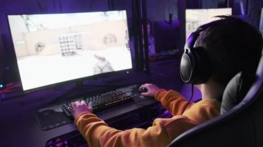 Genç oyuncu profesyonel bir oyun koltuğunda oturur ve E-spor kulübünde video oyunları oynar. Kulaklıklı bir çocuk bilgisayar kulübünde neon ışıkları olan bir video oyununa odaklanıyor. Oyun kulübünde genç, hobi olarak.