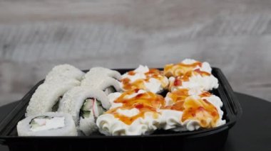 Suşi plastik kutuda döner, yakın plan. Philadelphia peynirli taze Japon suşisi, nori, susam, somon filetosu pilav, avokado ve salatalık. Plastik konteynıra konmuş suşi, paket yemek..