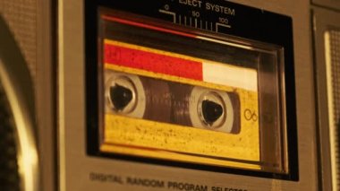 Retro teypte ses kaseti oynatıcısı. Eski sarı ses kasetini çalan bir pikap, yakın plan. Antika kasetler güvertede dönüyor. Konuşmalar kaydediliyor, 80 'ler, arama kaydı, retro çalma