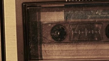 Kaset teypte çalınır. Yakın plan. Güvertede ses kaseti çalıyor ve dönüyor. Eski retro kaydediciyle klasik ses kaydı. Kaydı ara. Ses kaseti oynatılıyor. Makro