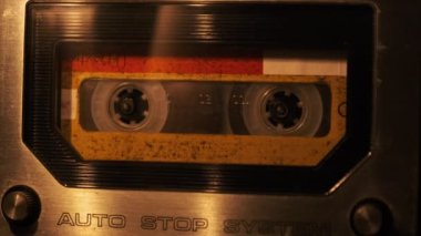 Retro bir teypte ses kaydı oynatılıyor. Plak çalar, yanıp sönen mum ışığında eski sarı bir kaset çalar, yakın plan. Eski bant makaraları güvertede dönüyor. Arama kaydı, çalma, 80 'ler