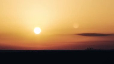 Timelapse of sunset in the orange sky over the horizon. Big bright red sun with sunrays moves down. Awesome epic cloud space, vibrant color. Time Lapse. Sundown in Yellow Sky