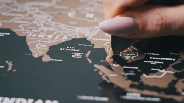 スクラッチワールドマップの表面にタイ国をスクラッチ 女性の手の消去旅行マップ上の国を訪問した 多くの国とスクラッチ世界地図 クローズアップ 企画旅行の概念 — ストック動画