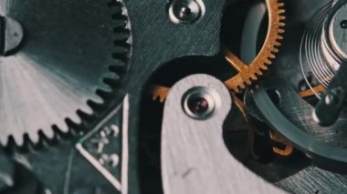 Clock mechanism rotates close-up. The working mechanism of round stopwatch spinning in macro. Detailed view of old retro clockwork gears, cogwheels and pendulum movement inside the ancient metal watch