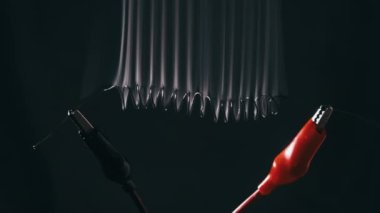 Nichrome kablosu yüksek elektrik akımı altında dumanla kırmızıya kadar ısınır. Nichrome lifi, laboratuvar güç kablolarına bağlı bir spiral şeklinde. Kablolar parlıyor, yüksek metal direnci var. Geçerli güç