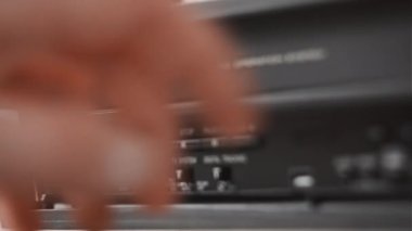Erkek eli, eski bir video kayıt cihazından VHS çekiyor. Arşivlenmiş video kasetlerin olduğu bir masadaki bir video oynatıcıdan VHS kaseti çıkar. VHS retro oynatıcı. Ev videosu kavramı, eski teknoloji