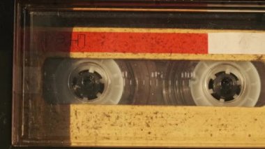 Kaset teypte çalınır. Yakın plan. Güvertede ses kaseti çalıyor ve dönüyor. Eski retro kaydediciyle klasik ses kaydı. Kaydı ara. Ses kaseti oynatılıyor. Makro