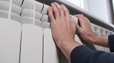 Mans eller evin ısıtma sistemi üzerinde sıcak tutmaya çalışıyor. Erkek avuçları duvardaki soğuk ısıtıcı kalorifere değiyor. Kötü ısıtma sistemi kavramı, dairede soğuk, kış mevsimi.