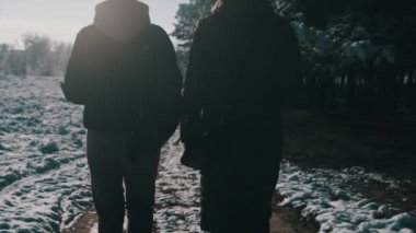 İki kız kış ormanında el ele yürüyorlar. Yavaş çekimde, dikiz aynasıyla. Parlak güneşe karşı kar yolunda yürüyen kadın kız arkadaşlar. Sevgi dolu bir çift adımın arka görüntüsü. LGBT, lezbiyen