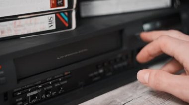 Video oynatıcıdan VHS kaseti çıkar. Erkek el, birçok arşivlenmiş video kaset içeren eski bir video kayıt cihazından VHS çekiyor. VHS retro oynatıcı. Ev videosu kavramı, eski teknoloji