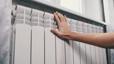 Erkek el, duvardaki soğuk ısıtıcı kalorifere dokunuyor. Mans Palm, evin ısıtma sisteminde ısınmaya çalışıyor. Kötü ısıtma sistemi kavramı, dairede soğuk, kış mevsimi.