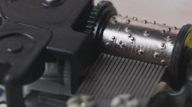 Retro music box mechanism with spinning cylinder and cogs in macro. Old music box clockwork device with rotating drum with projections touching the records creates music. Toy barrel organ rotates. 4K