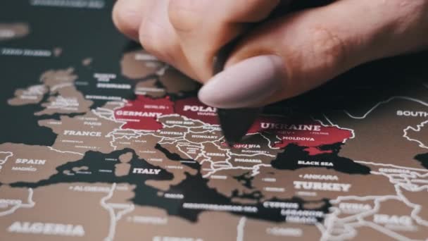 スクラッチ世界地図の表面にルーマニアのスクラッチ国 ヨーロッパ諸国と女性の手スクラッチ世界地図 クローズアップ スクラッチは 旅行地図上の国を訪問した 傷の上で国を消す — ストック動画