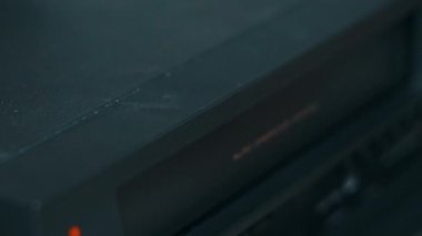 Video oynatıcıdan VHS kaseti çıkar. Erkek el bir düğmeye basar ve birçok arşivlenmiş video kasetle birlikte masadaki klasik video kayıt cihazından VHS 'yi çıkarır. VHS retro oynatıcı. Ev videosu, eski kaset