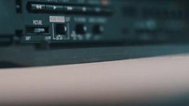 Video oynatıcıya VHS kaset ekle. Masada bir sürü arşivlenmiş video kaset kaydedici var. Kadın eli eski VHS bandını retro oynatıcıya sokuyor. Ev videosu, nostalji.