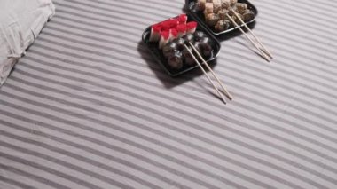 Suşi plastik bir kapta yuvarlanır ve çift kişilik bir yatakta yatar. Bir çift için romantik bir akşam. Suşi yatak odasındaki beyaz çarşafa serildi. Yaşam tarzı, nefis bir akşam, insan yok..