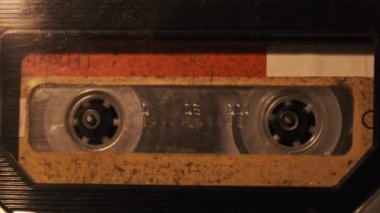 Retro bir teypte ses kaydı oynatılıyor. Plak çalar, yanıp sönen mum ışığında eski sarı bir kaset çalar, yakın plan. Eski bant makaraları güvertede dönüyor. Arama kaydı, çalma, 80 'ler