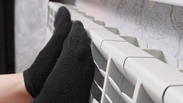 靴下の女性の足は暖かい保つことを試みる暖房ラジエーターに触れる 貧しい暖房システムの概念は アパートで寒い 冬の季節 暖房の問題 中央暖房 冷たい人は暖めようとする — ストック動画