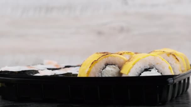 プラスチック製の箱の中の寿司ロールが回転し 閉じます フィラデルフィアチーズ サーモンフィレご飯 アボカドとキュウリと新鮮な日本の寿司 プラスチック容器に入れた寿司 持ち帰り用の食べ物 — ストック動画