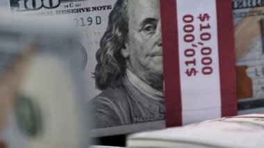 Dolarlar yakın planda toplanır. 10 bin Amerikan Doları demetleri banknotlar halinde masanın üzerinde dönüyor. 100 dolarlık banknotlar. Makro olarak yığınla para, büyük para, iş yatırımı. 4K