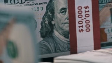 10 bin Amerikan Doları demetleri banknotlar halinde masanın üzerinde dönüyor. 100 dolarlık banknotlar. Dolarlar yakın plan çekimde dönüyor. Makro olarak yığınla para. Büyük paralar, iş yatırımları. 4K