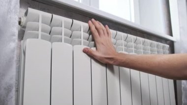 Erkek el, duvardaki soğuk ısıtıcı kalorifere dokunuyor. Mans Palm, evin ısıtma sisteminde ısınmaya çalışıyor. Kötü ısıtma sistemi kavramı, dairede soğuk, kış mevsimi.