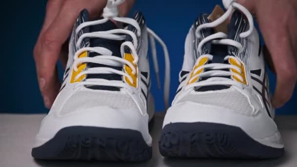 男性的手移动新的现代鞋子来模仿走路 模仿穿着一双白色运动鞋在桌子上走路的样子 时髦的青年运动鞋 健康的生活方式4K — 图库视频影像