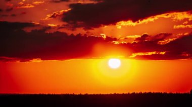Timelapse Muhteşem Gün batımı bulutlarla birlikte turuncu gökyüzünde aşağı iniyor. Parlak turuncu güneş ufuk çizgisinde katmanlı bulutların arkasında hareket ediyor. Destansı bulut uzayı, canlı bir renk. Zaman aşımı. Güzel gün batımı