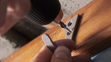 Kendini beceren bir zanaatkar elektrikli tornavida kullanarak tahtaya vida sokuyor. Vida kancası, yakın plan elektrikli matkapla duvardaki tahta kancaya takılıyor. El yapımı, kendin yap.