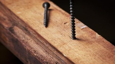 Vidalar tahta tahtaya tornavidayla vidalanmış, yakın plan. Kendi kendini beceren bir vida makro matkapla kendi yerine saplanmış. Tahtayı kesen ipliklerin dönüşü.