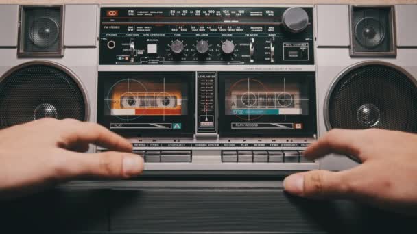 老式保险盒播放器的音乐 来自旧盒式磁带的模拟声音 男性按下桌子上两个盒式磁带唱机上的播放按钮 听音乐 80年代的复古录音机 — 图库视频影像