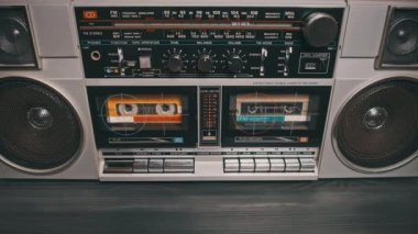 Masadaki klasik müzik kutusuyla ses kasedi çalıyorum. Masadaki iki kaset çalar üzerindeki erkek el ile oynatma düğmesine bas ve müzik dinle. Hoparlörlü gümüş retro radyo, 80 'ler.