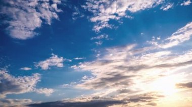 Siren bulutları mavi gökyüzünde güneşle birlikte hareket eder, zaman kavramı. Açık beyaz ve ara sıra gri bulutlu bulutlu geniş bir manzara. Gökyüzü arkaplanının panoramik görüntüsü. Zaman Süreleri.